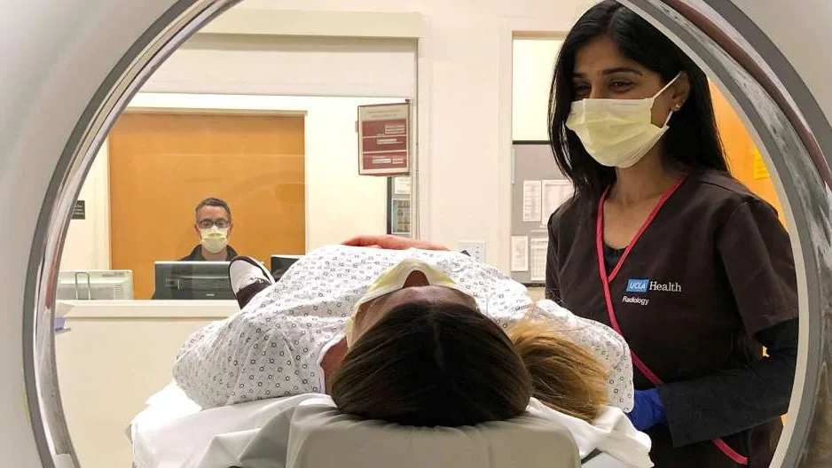 Photo of patient in MRI device with assisting Radiologist 